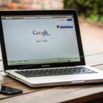 Un ordinateur portable affiche Google, un smartphone repose à côté sur du bois