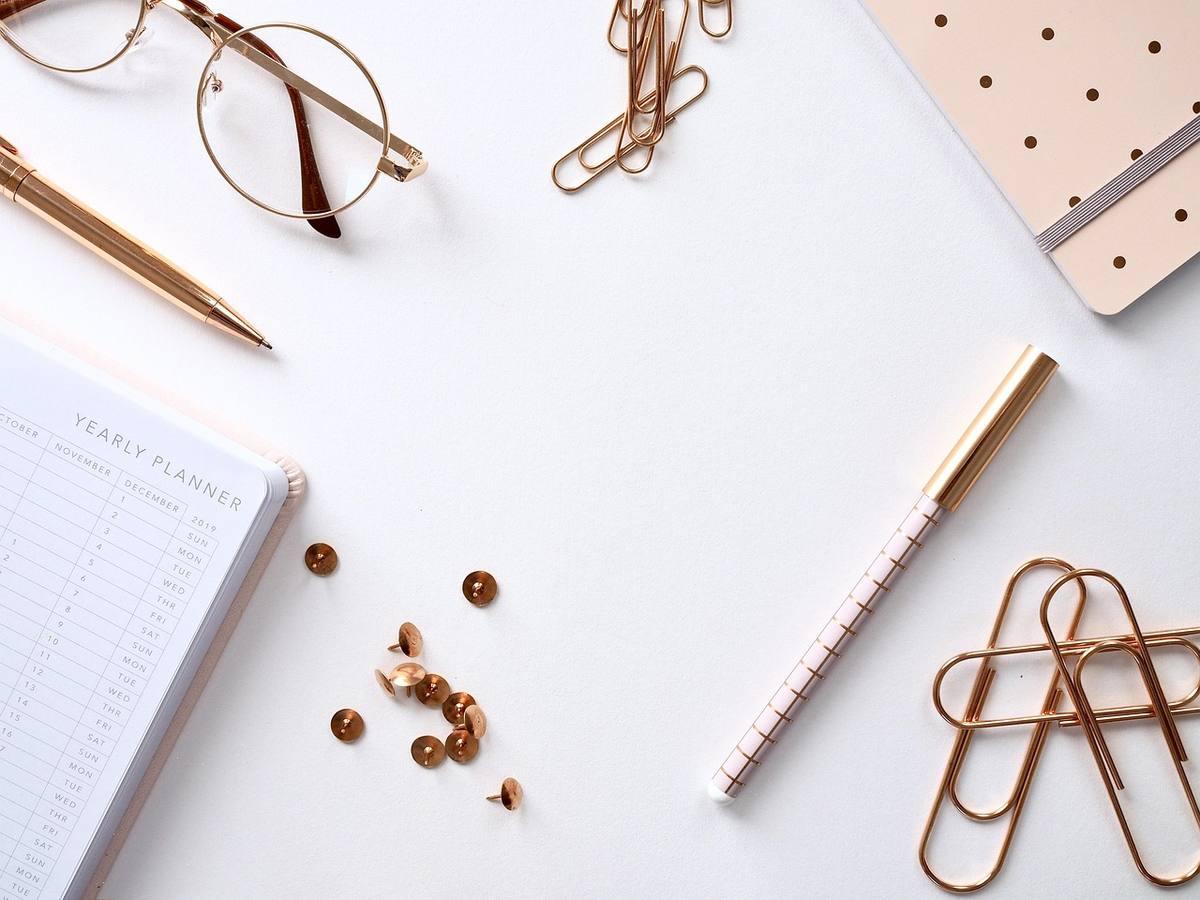 Vue d'un bureau avec cahier, stylo, lunettes, trombones et accessoires