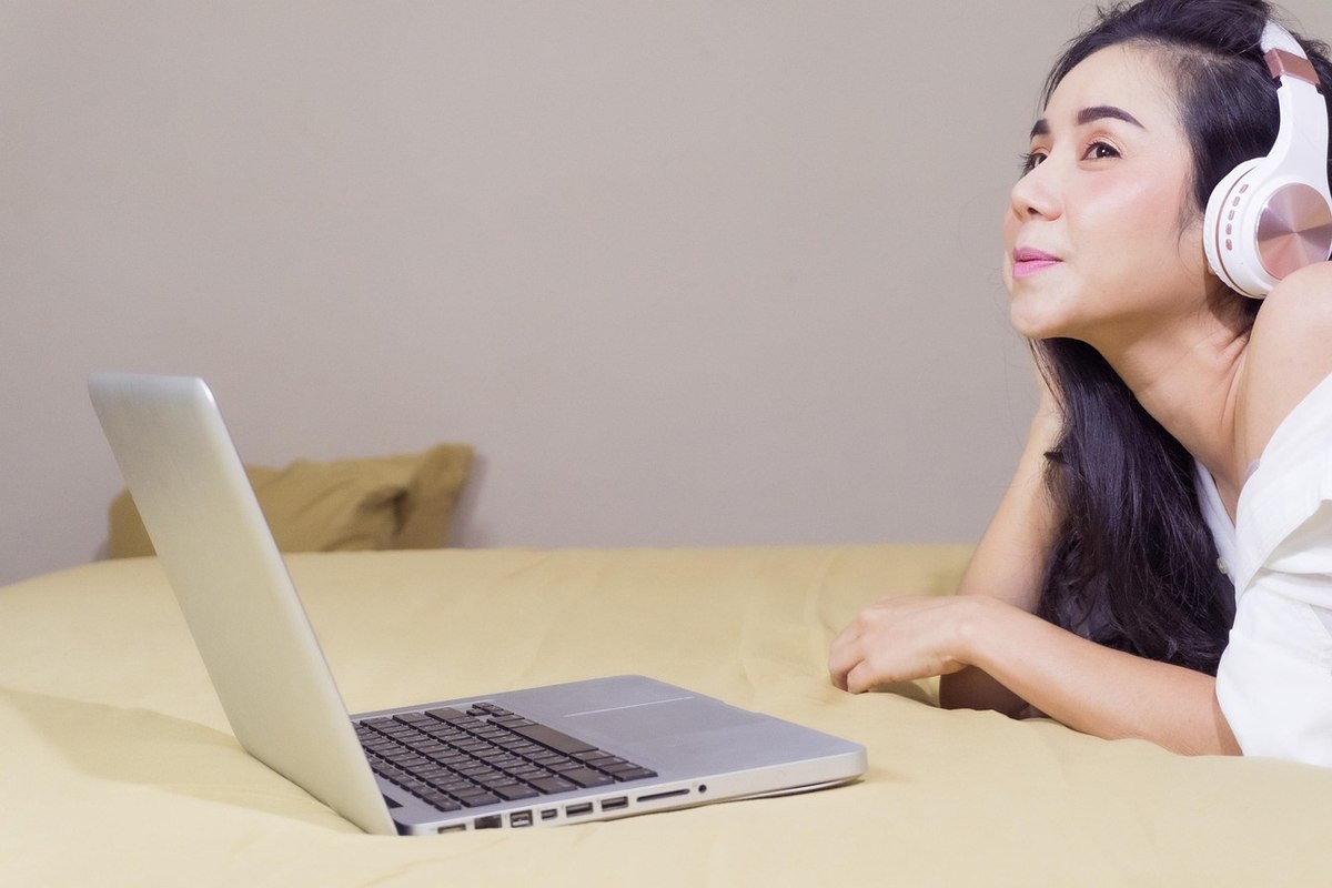 Une femme écoute de la musique via casque sur son ordinateur Une femme écoute de la musique via casque sur son ordinateur